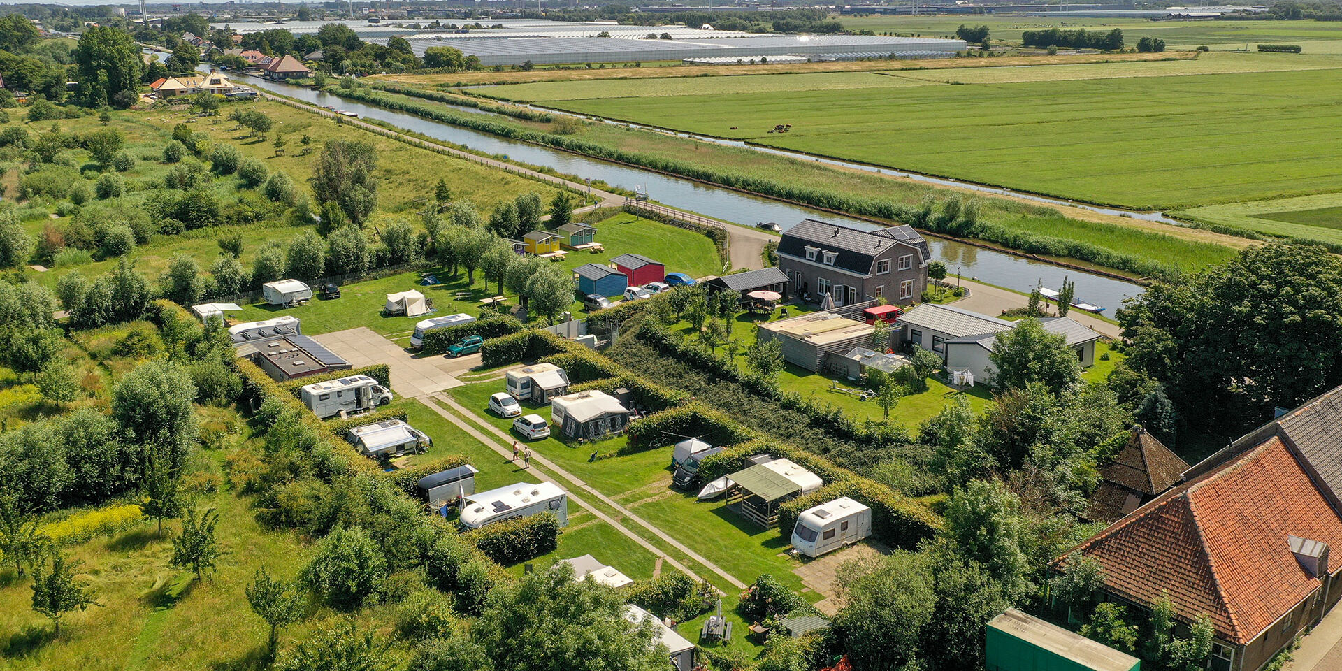luchtfoto van Minicamping Zwetzone in het Westland met rivier de Zweth, de polder van Midden-Delfland en de skyline ven Delft
