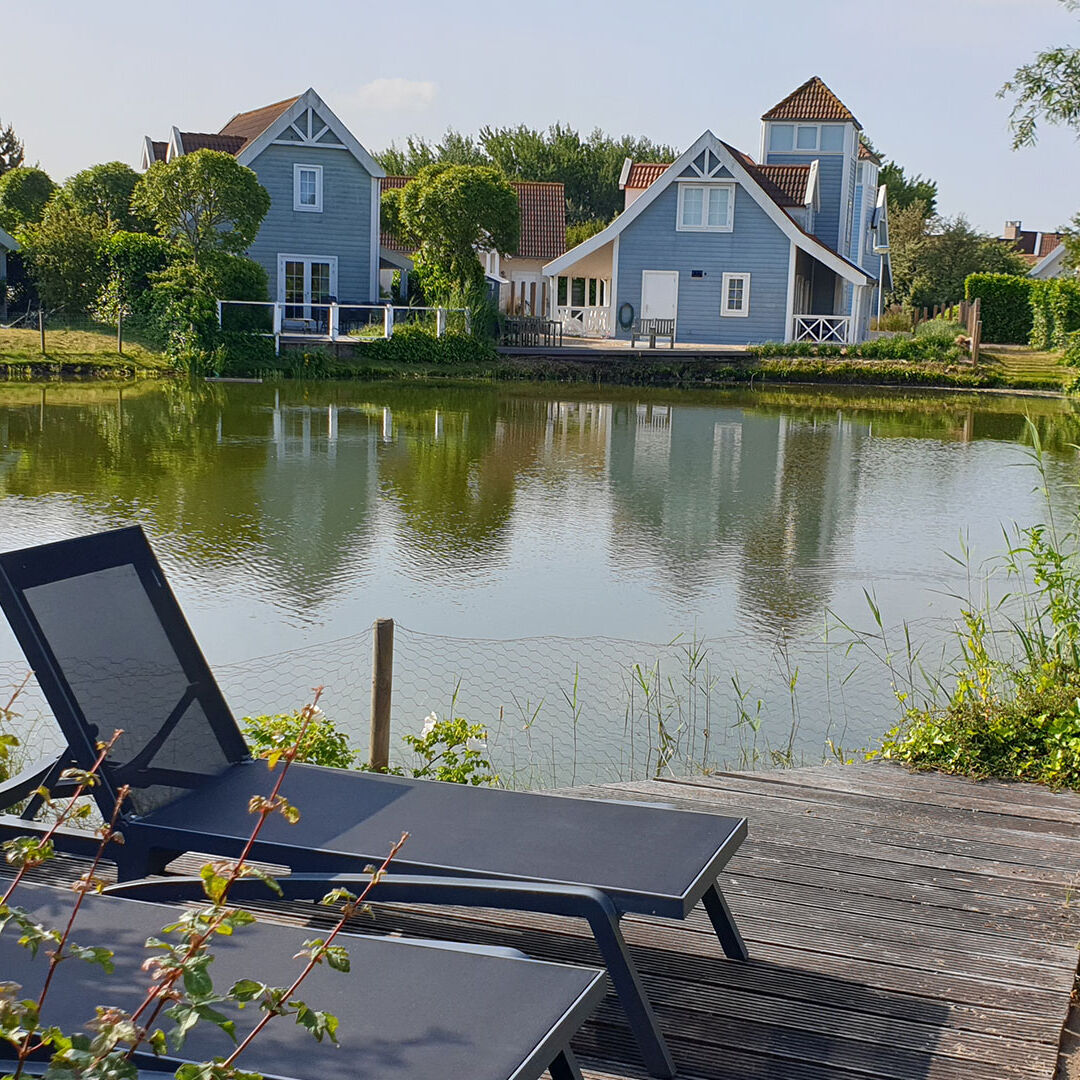 zithoek met twee ligbedden aan een plas tussen de luxe duinvilla's van Duynparc De Heeren van 's Gravensande in het Westland