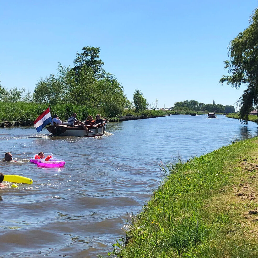 kinderen zwemmen met roze en gele drijvers in de rivier de zweth voor de deur bij Minicmping Zwetzone in het Westland