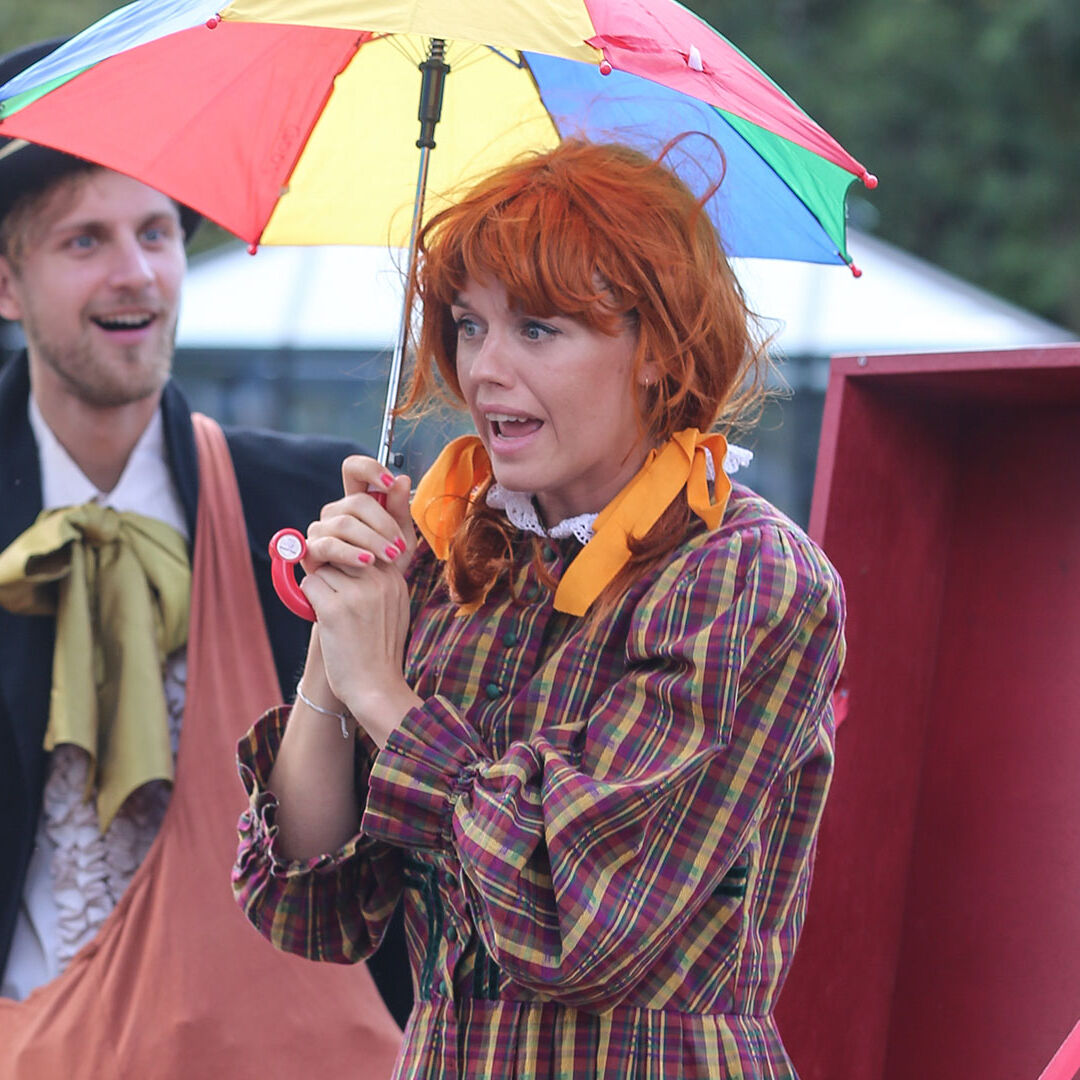 verklede straattheater artiesten met parasol en grappige kleren houden een optreden voor kinderen tijdens een festival van Westand Cultuurweb in het westland