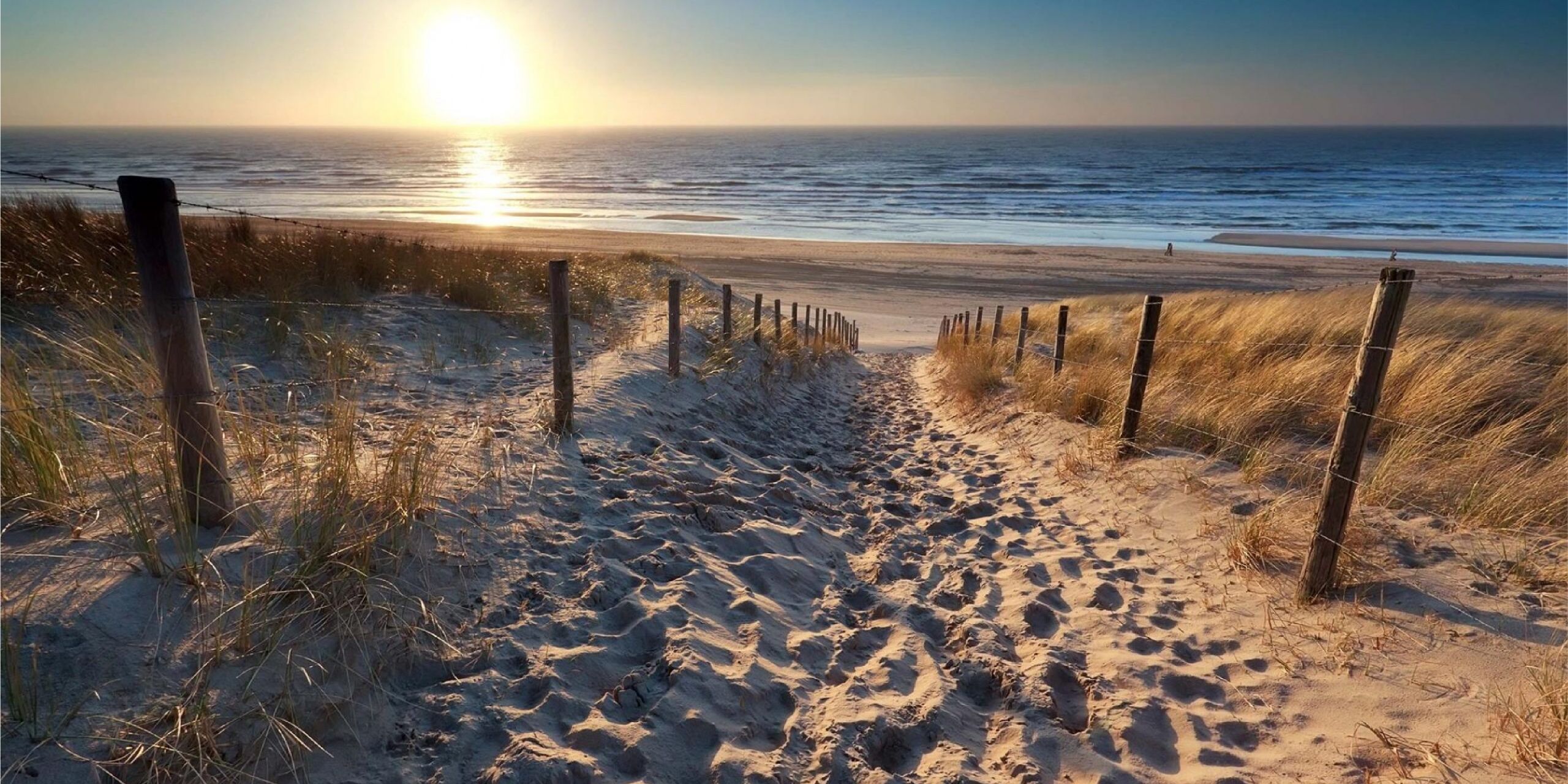 Foto van een strandopgang naar het Westlandse strand met ondergaande zon