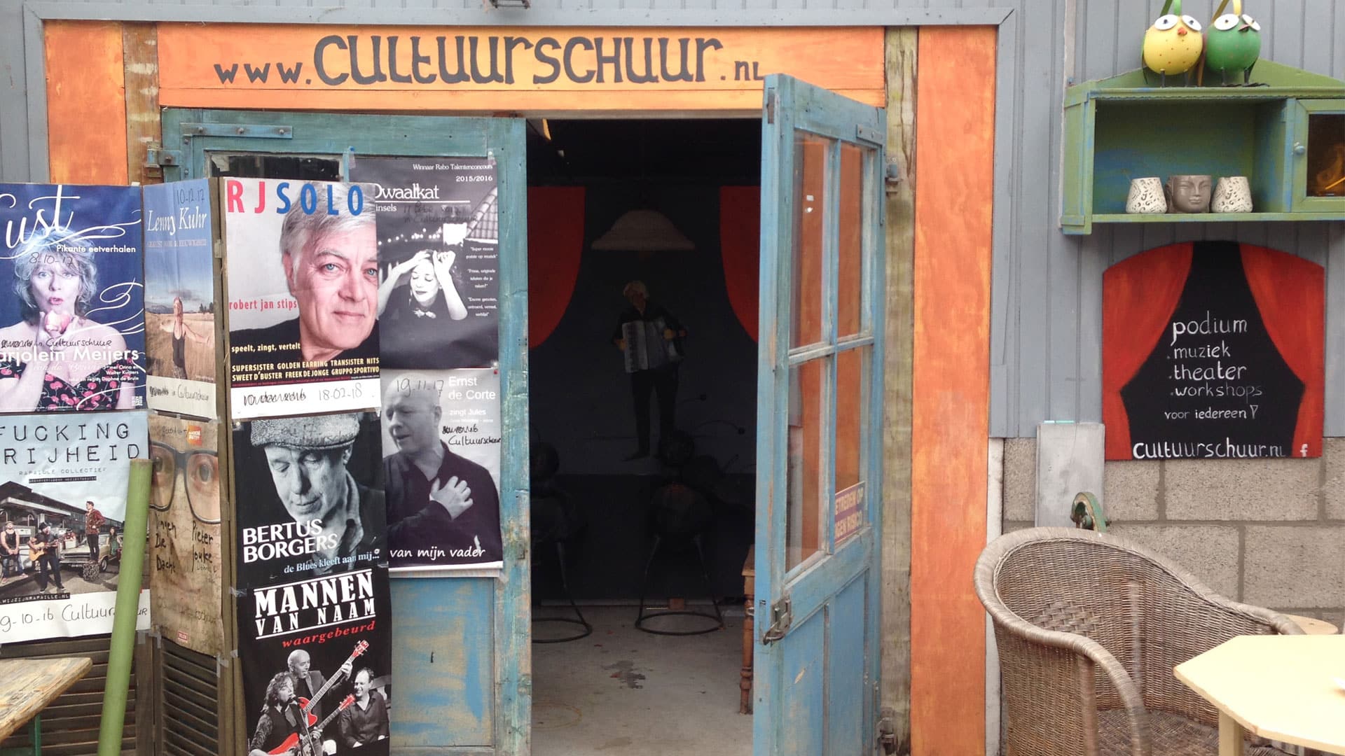 Houten deur beplakt met poster van artiesten is de toegang tot de Cultuurschuur in het Westland