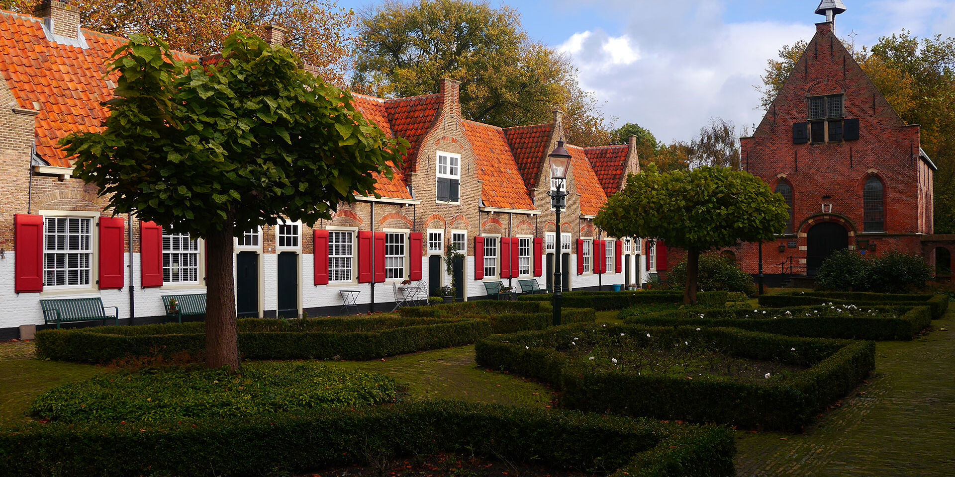 Oude huisjes met oranje dakpannen en rode luiken in het Heilige Geesthofje in Naaldwijk in het Westland