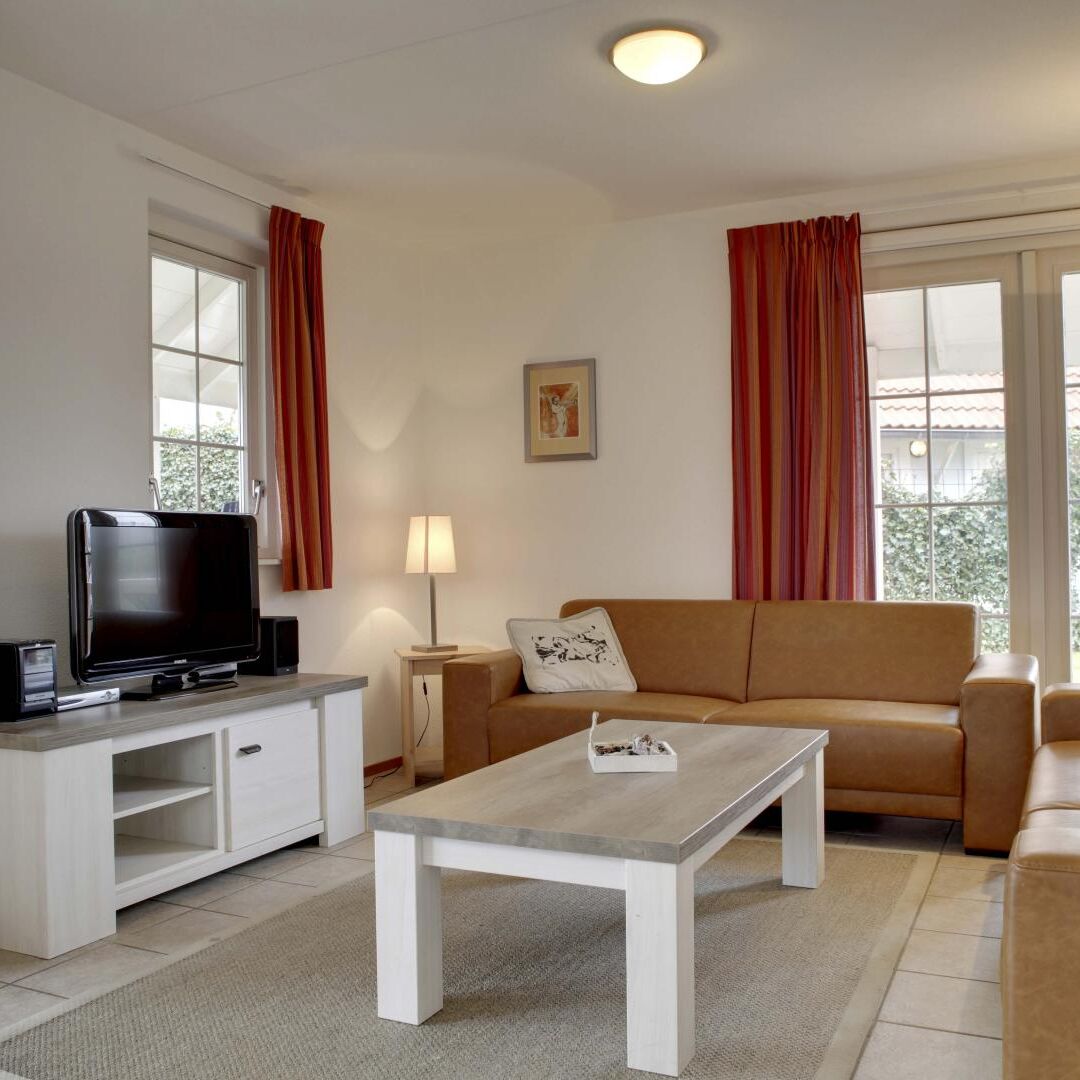 zithoek met witte en lichtbruine meubels van een luxe villa bij Duynparc De Heeren van 's Gravensande in het Westland