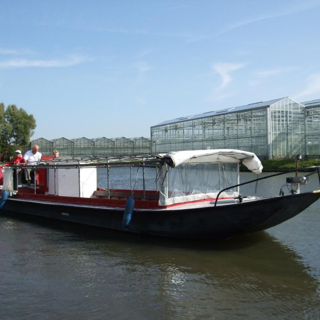 rondvaartboot van rondvaartbedrijf de Gantel vaart met open luifels langs kassen in het westland