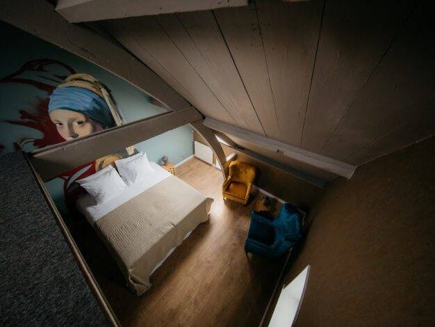 kamer van Boutique Hotel De Gravin in het Westland met bed, houten balken en een muurschildering van het meisje met de parel van Johannes Vermeer
