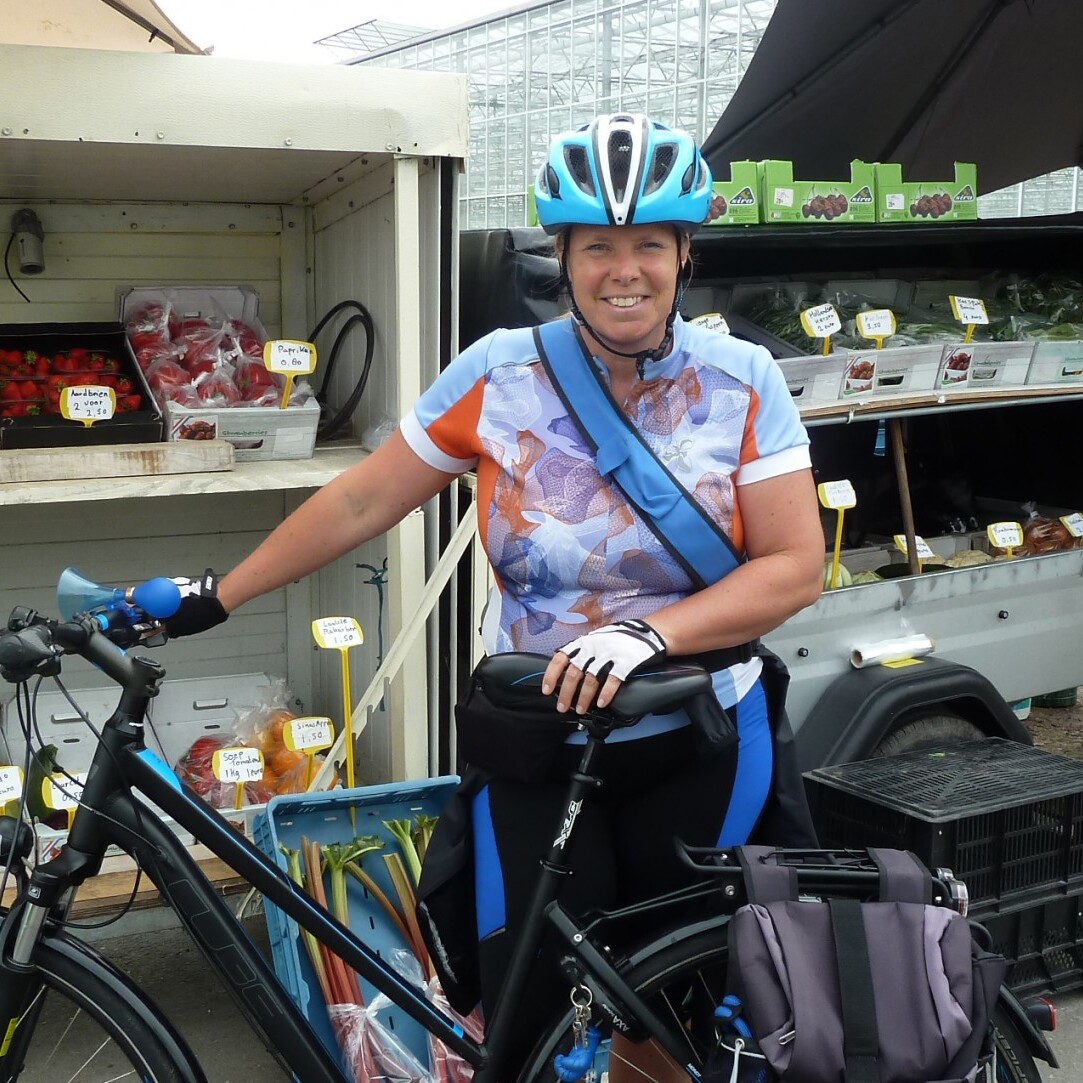 Marja van der Ende poseert met haar fiets voor een stalletje met streekproducten uit het Westland