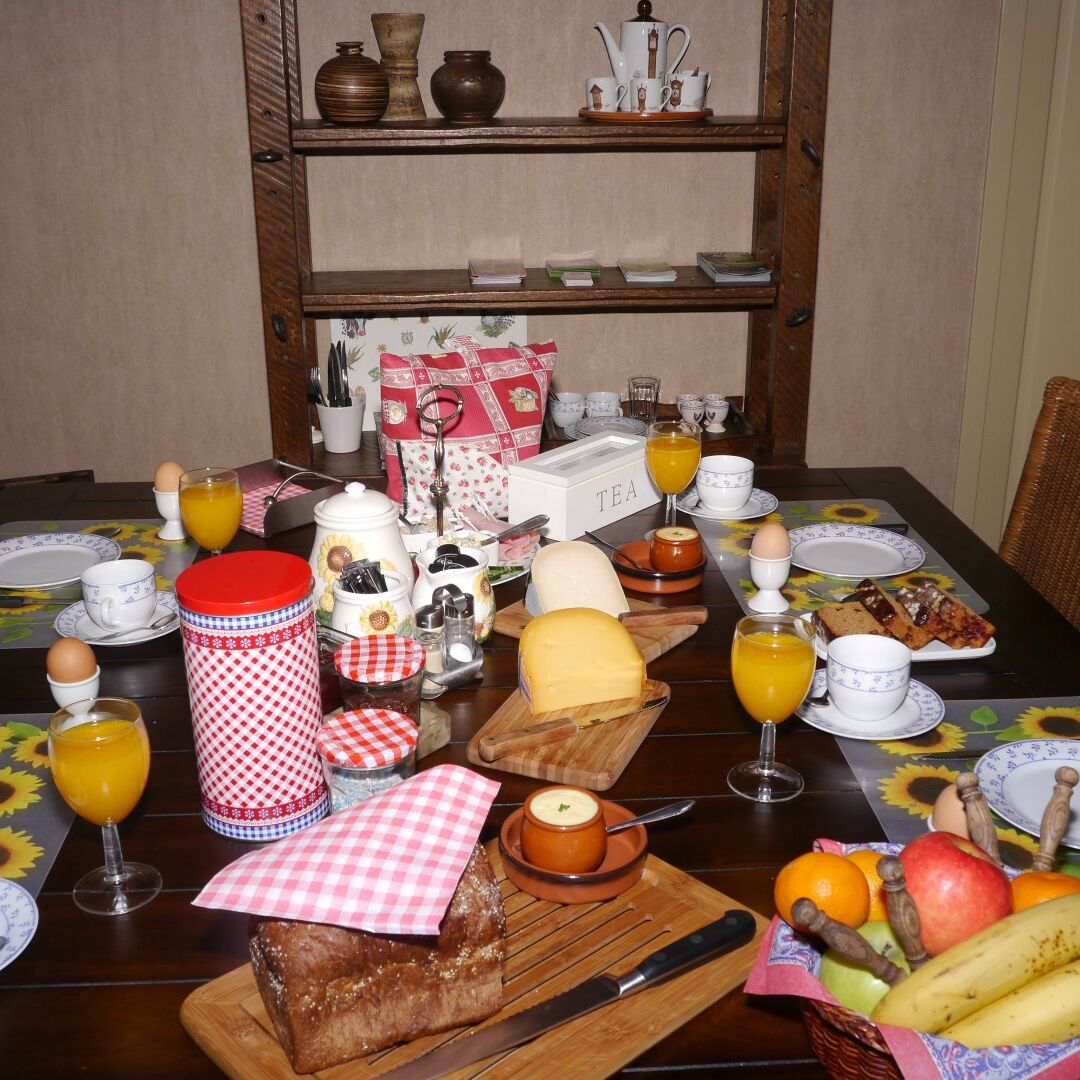 ontbijtafel gedenkt met vers brood, kaas, eieren, jus d'orange en fruit in de eetkamer van B&B de Hooiberg in het Westland