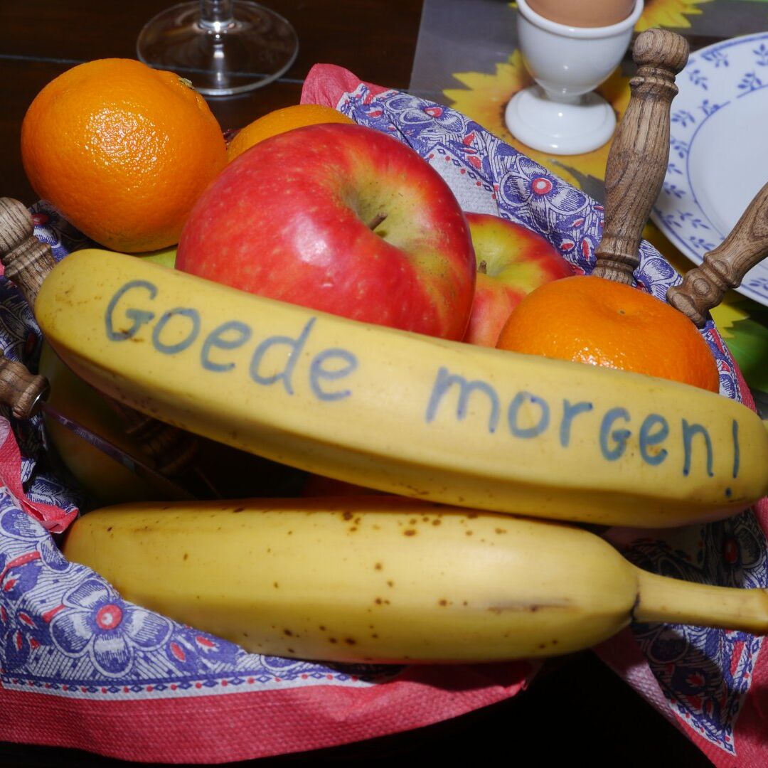 fruitschaal met bananen, appels en sinaasappels. Op de banaan staat geschreven ' Goede morgen' in B&B de Hooiberg in het Westland