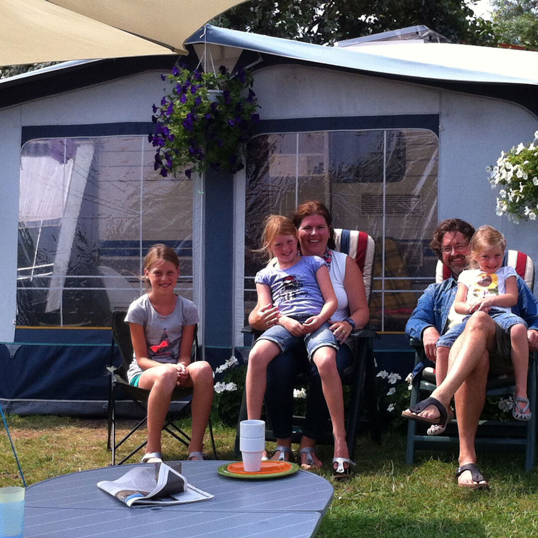 Gezin met vader en moeder en 3 kinderen voor een bungalowtent op de camping van Strandpark Vlugtenburg in het Westland