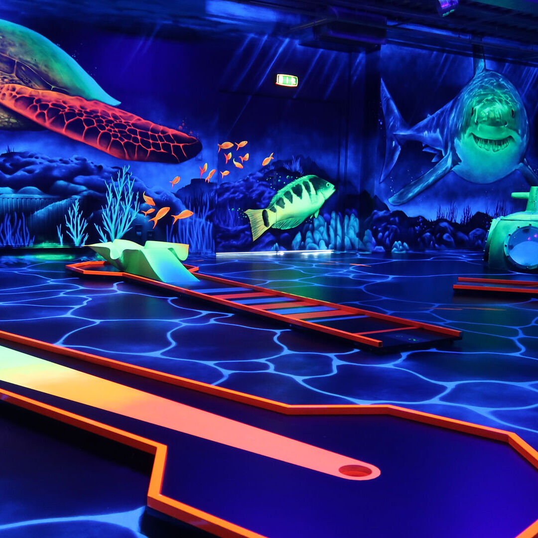 Indoor minigolfbaan met fluoriscerende verlichting en versiering alsof je onder water bent met haaien en schildpadden bij Van der Ende Racing Inn in het Westland