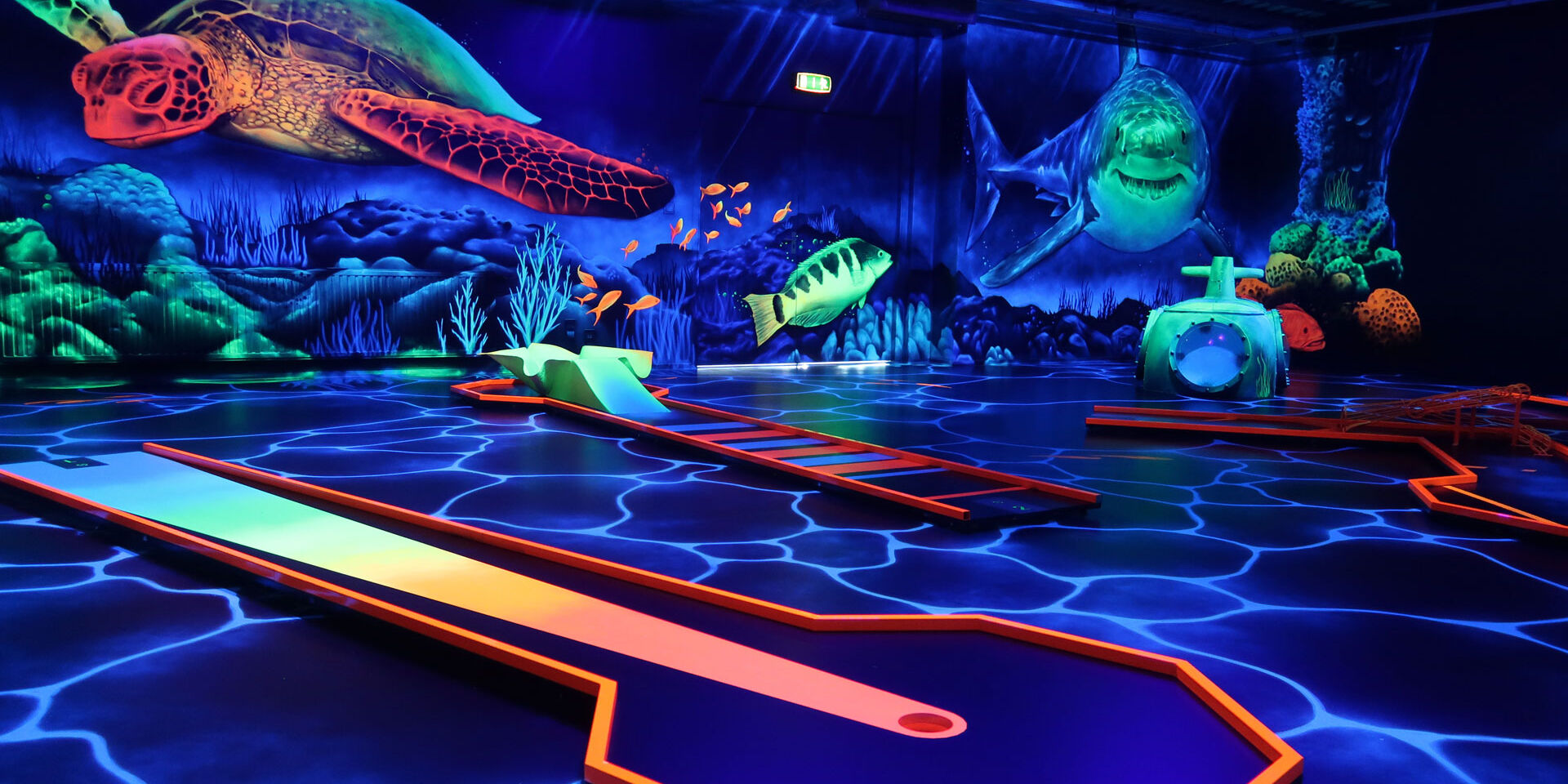 Indoor minigolfbaan met fluoriscerende verlichting en versiering alsof je onder water bent met haaien en schildpadden bij Van der Ende Racing Inn in het Westland