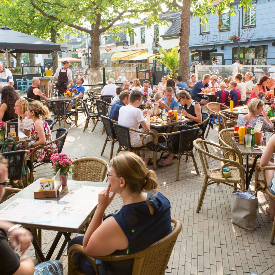 zomers terras vol met jonge mensen en gezinnen die genieten van eten en drinken in 's Gravenzande in het Westland