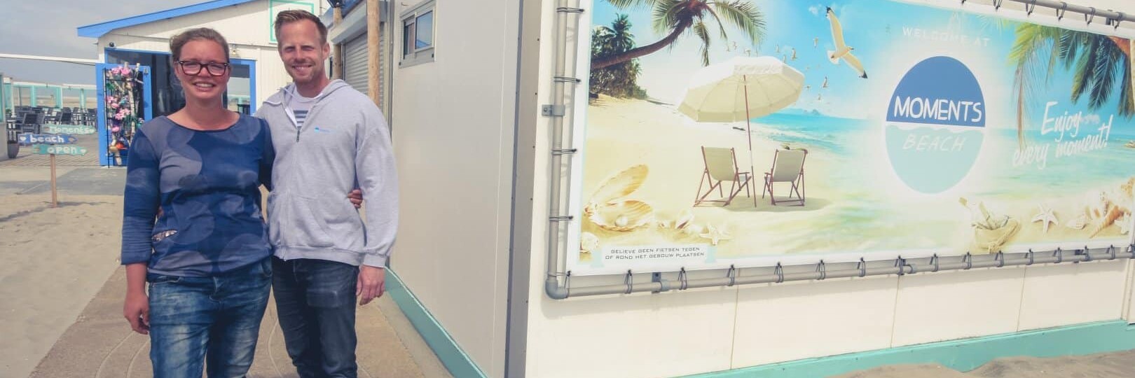 Eigenaren Roy en Danielle naast hun strandtent Moments Beach op het strand in het Westland