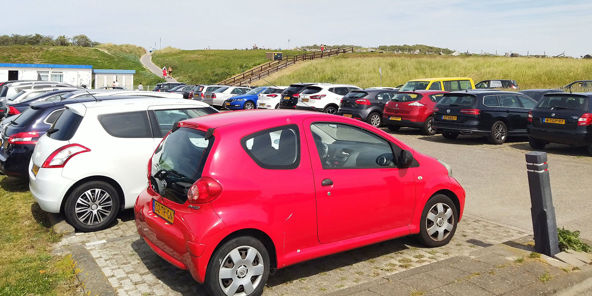 parkeerplaats vol met geparkeerde auto's aan het strand in het westland