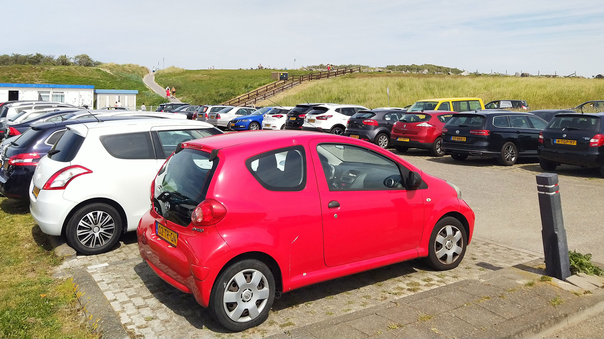 parkeerplaats vol met geparkeerde auto's aan het strand in het westland