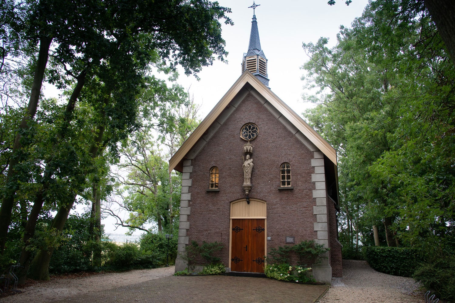 Vooraanzicht van de Lambertuskerk, gebouwd in 1872 door jhr. Augustinus van Rijckevorsel voor zijn pachters. De kerk wordt omgeven door een bostuin in Heenweg in het Westland