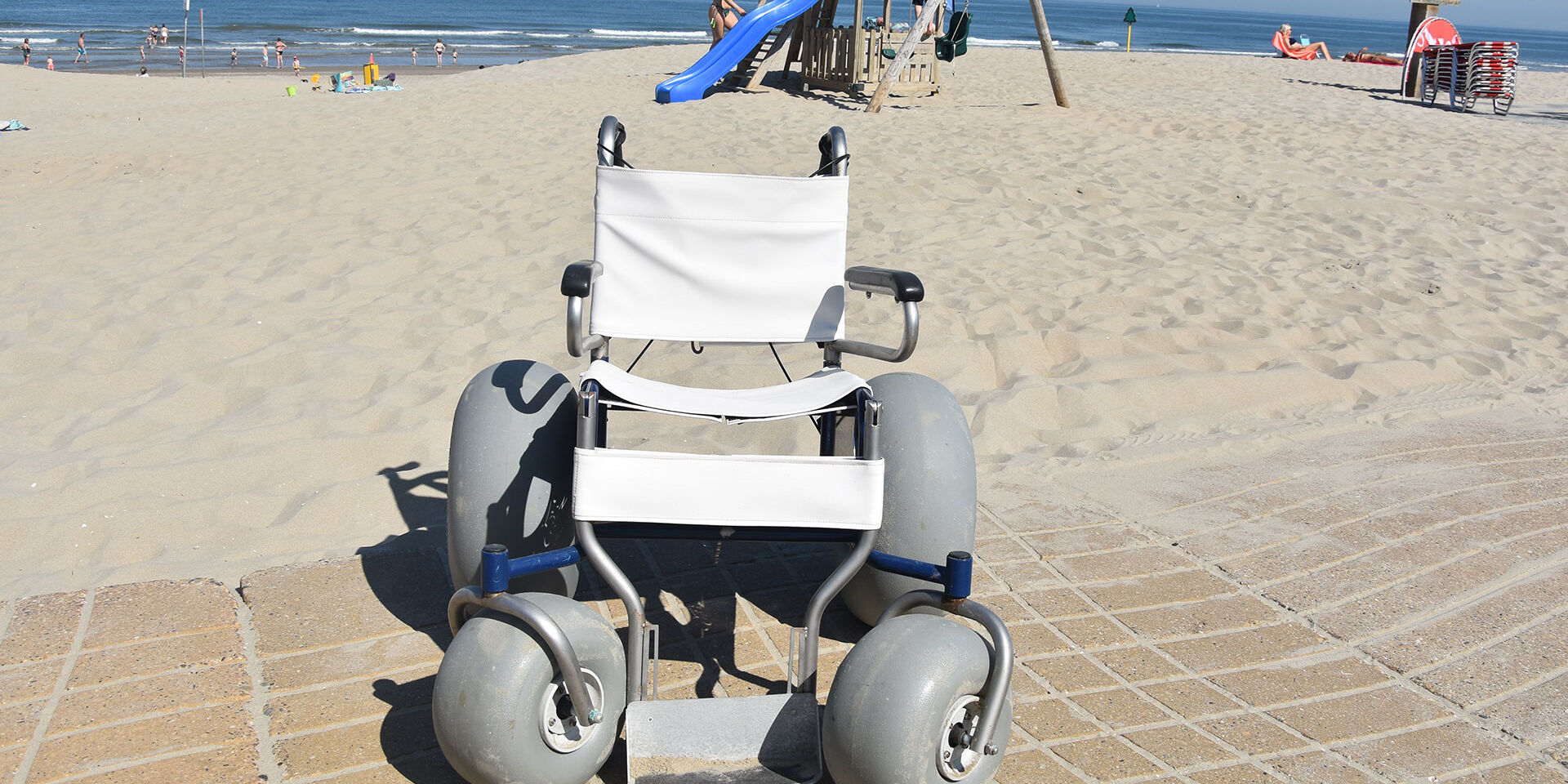 strandrolstoel voor gehandicapten met brede banden staat op het strand in het westland klaar om gebruikt te worden door mindervaliden voor een rit op het strand van het Westland