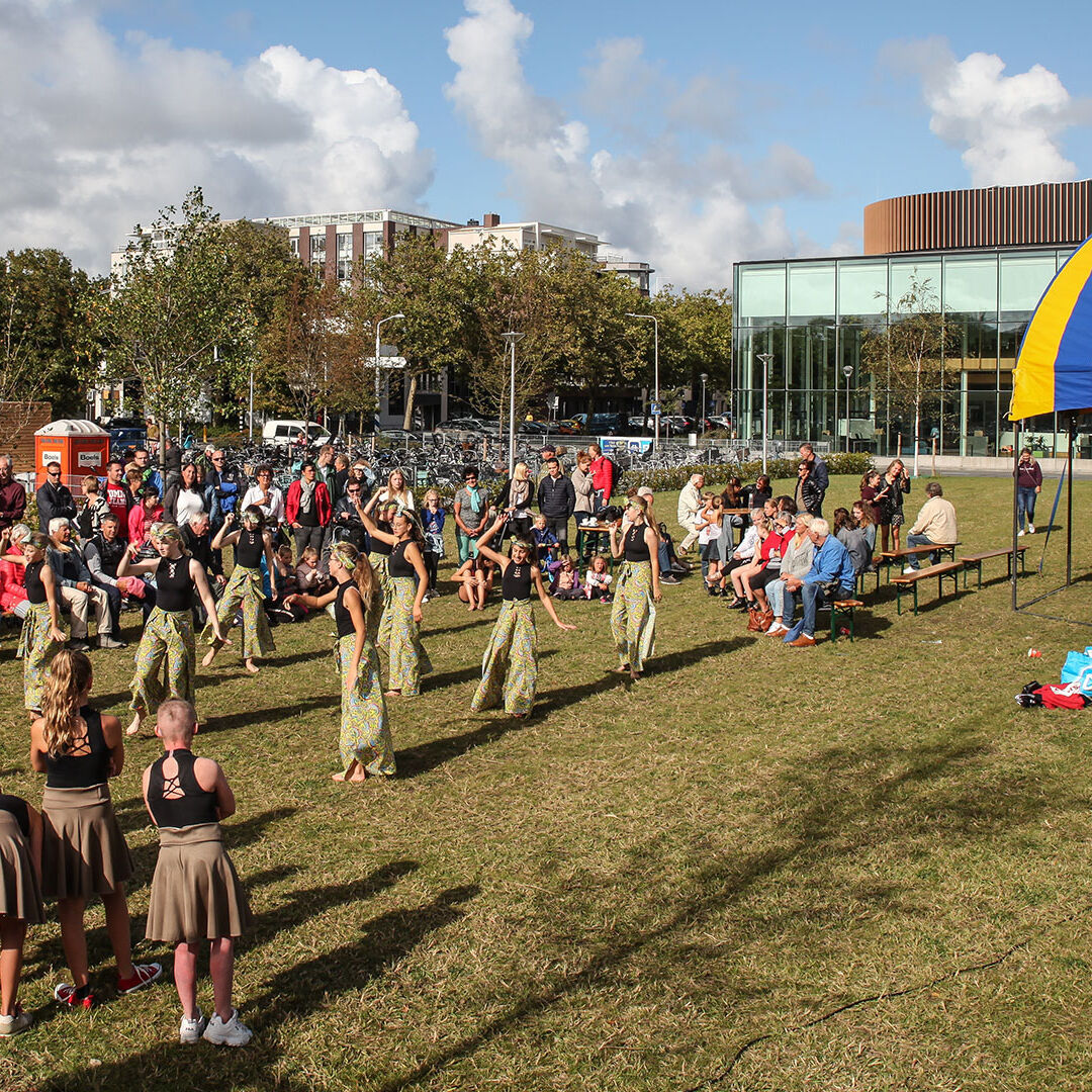 optreden van een groep danseressen op het grasveld naast het gemeentehuis van de gemeente Westland en naast een blauw-geel gestreepte circustent tijdens cultuurfestival Podium Westland