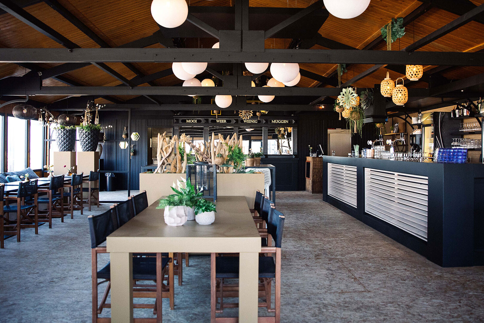 foto van een lange eettafel en bar binnen bij strandtent Bondi Beach Club in Monster in het Westland