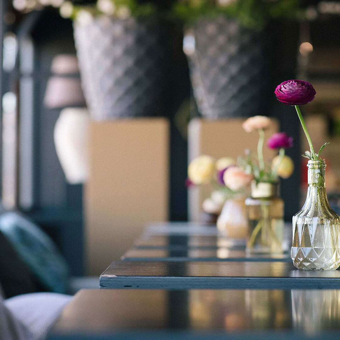 detailfoto van tafels met kleine vaasjes met bloemetjes binnen bij strandtent Bondi Beach Club in het Westland