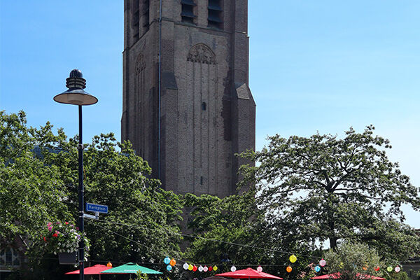 dorpskern van Monster met kerktoren en in de voorgrond een terras met kleurige parasols