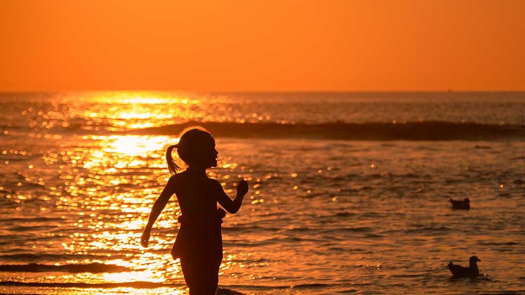 meisje spelen in de zee strand zonsondergang