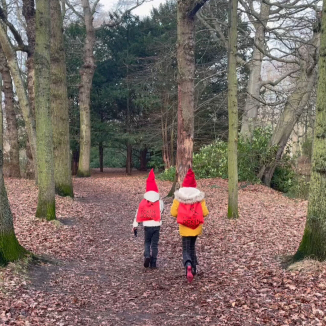 twee kabouters in het bos kinderen met rode puntmuts en rugzak kabouterpad wandelen