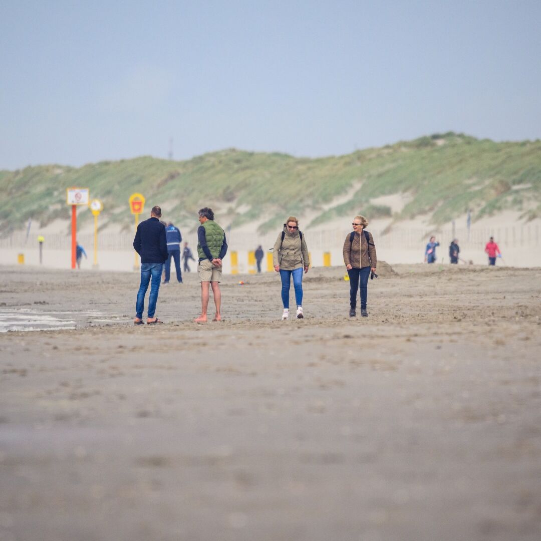 wandelaars op het strand van het Westland in het najaar met jassen aan